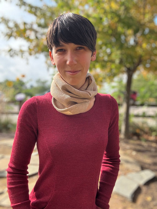 Woman wearing tan merino wool neck warmer outdoors in autumn fall and a merino wool red dress