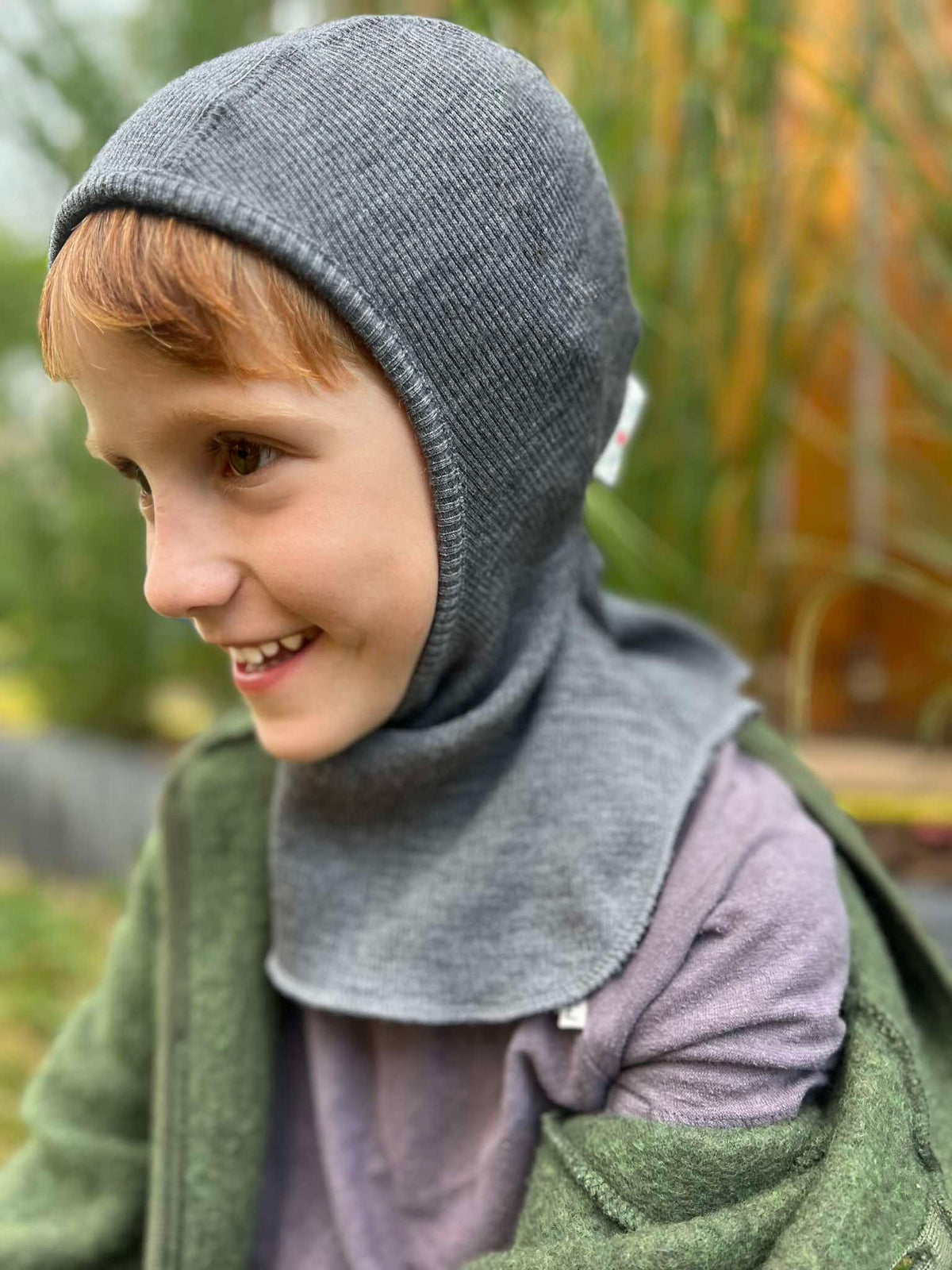 snug fitting full coverage merino wool kids balaclava in a dark grey melange color on a school age boy by manymonths